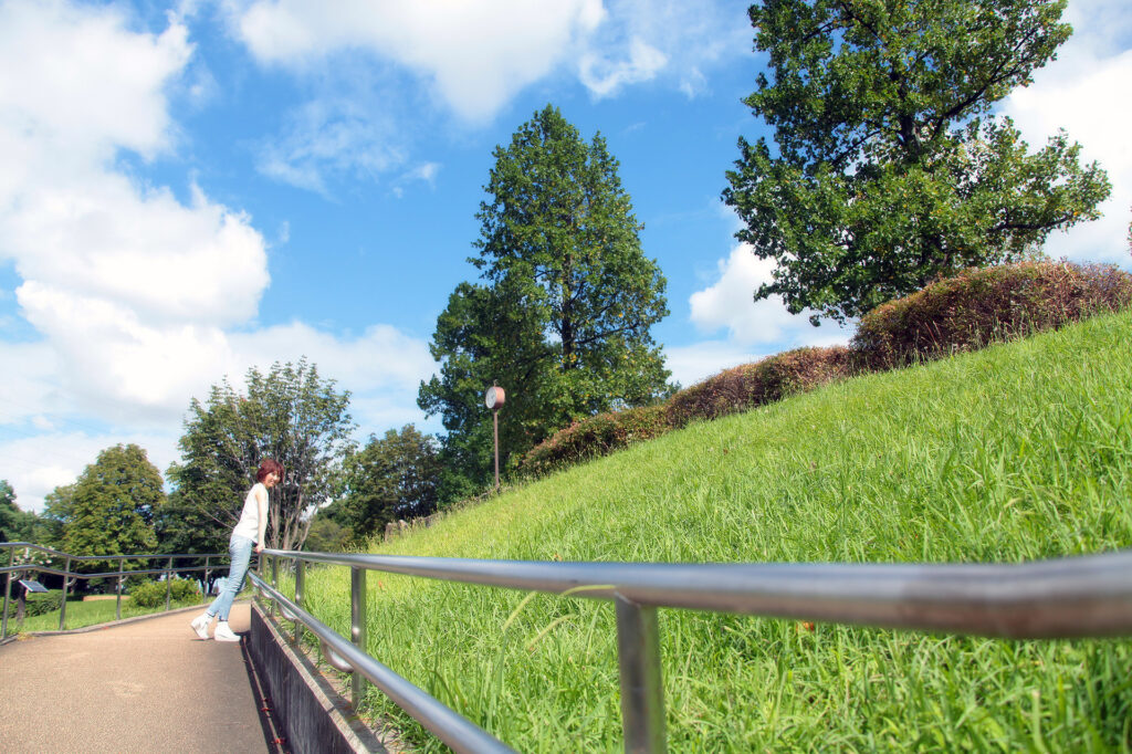 自然の中で静かに立つノリコの姿。自然体の美しさとYURUKU®の理念を映したイメージ写真。