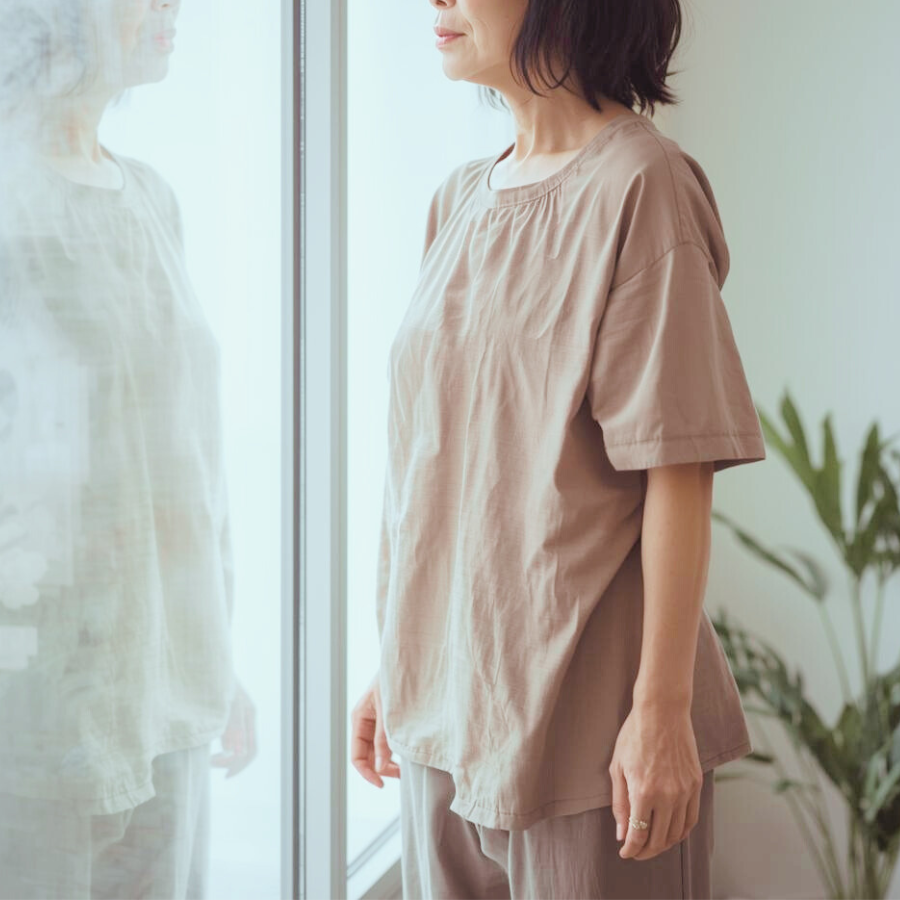 鏡ではなく窓ガラスにうっすら映る自分の姿を、ぼんやりと見つめる女性の写真