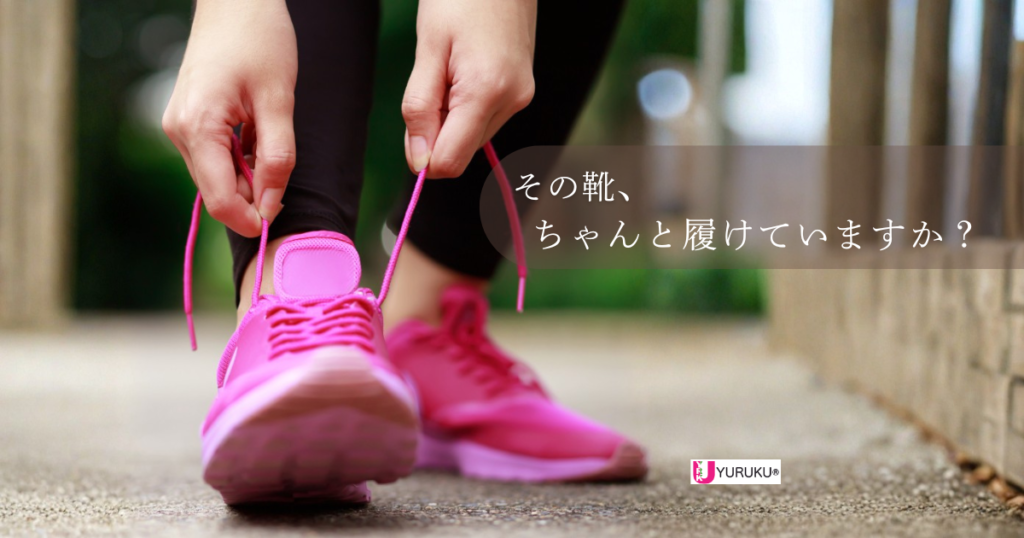 ピンクのスニーカーの靴紐を結ぶ女性の足元