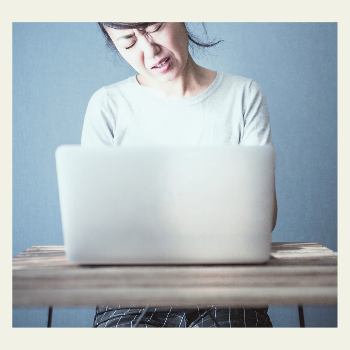 オンラインレッスン前に、PCの前で不安そうに画面を見つめる女性