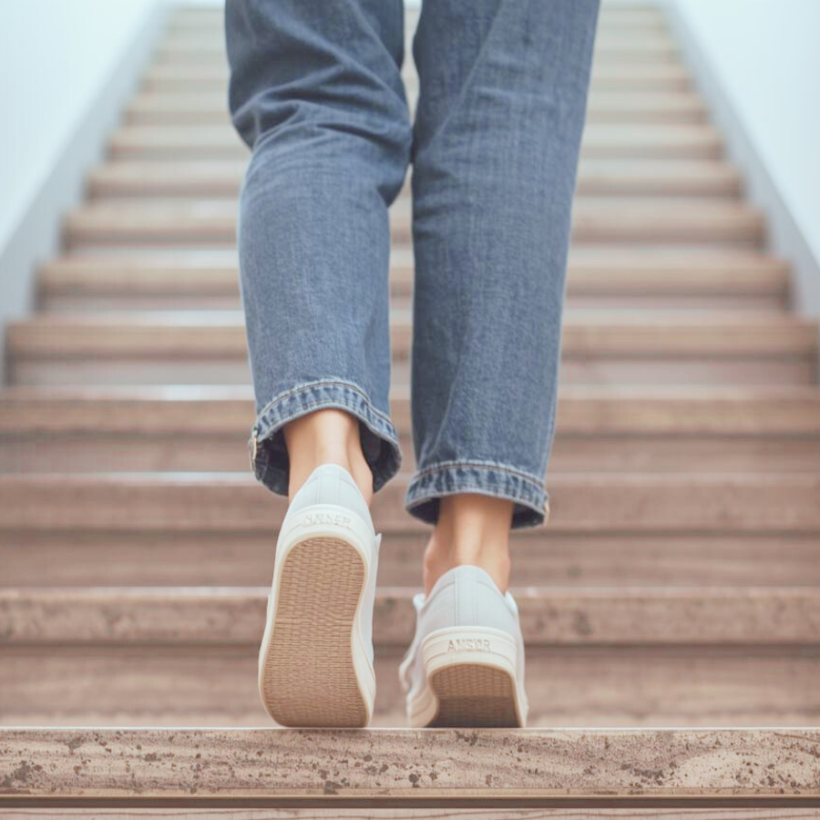 階段を一段上がる女性の足元。一歩踏み出す瞬間を表す写真