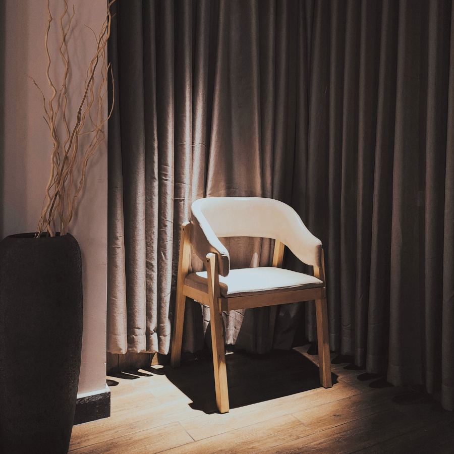 体の痛みに意識が向きすぎ、感覚の余白を失っている状態を象徴する、静かな室内の椅子