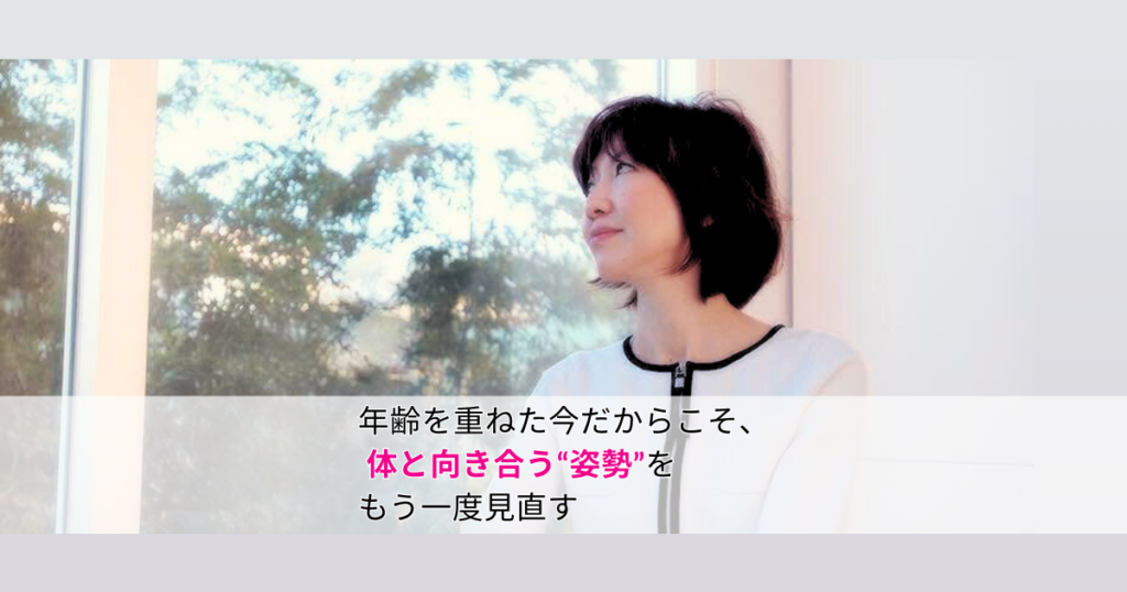 年齢を重ねた女性に向けて、体との向き合い方を伝える姿勢改善指導者ノリコが、窓の外の木々と空を見つめて立つ姿
