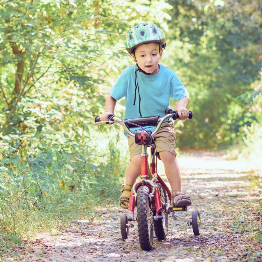 補助輪付き自転車に乗り、不安定ながら楽しそうな表情の男の子
