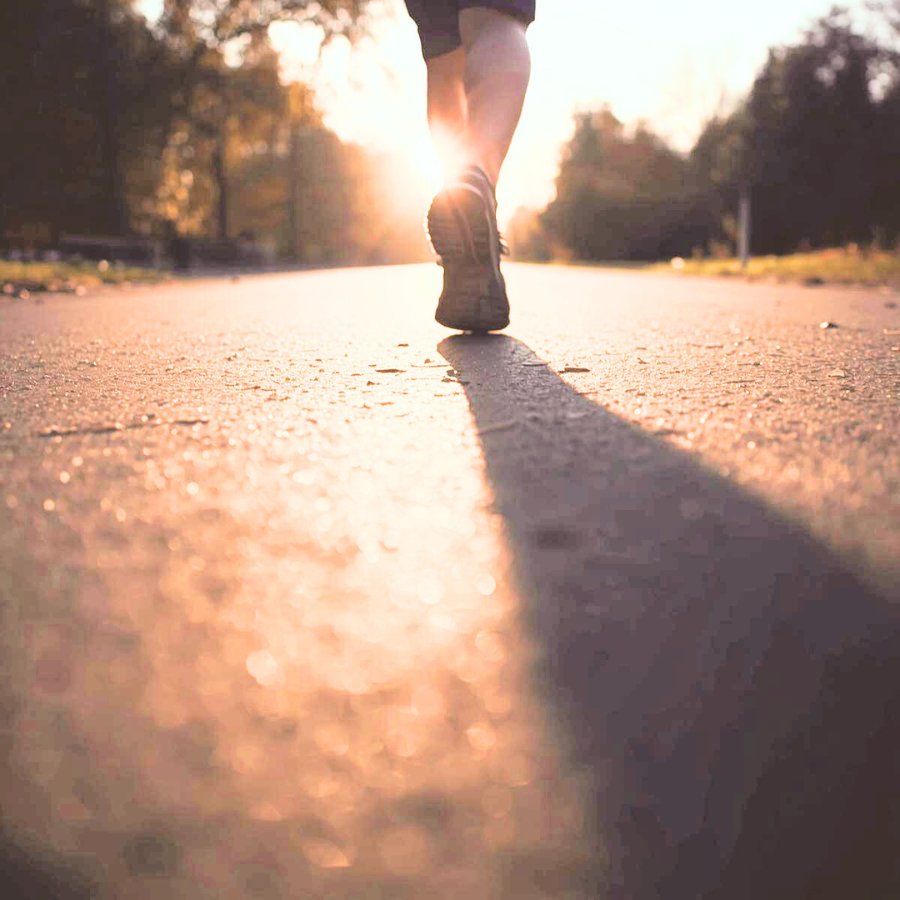 夕方の長い影の中で一歩踏み出す女性の足元