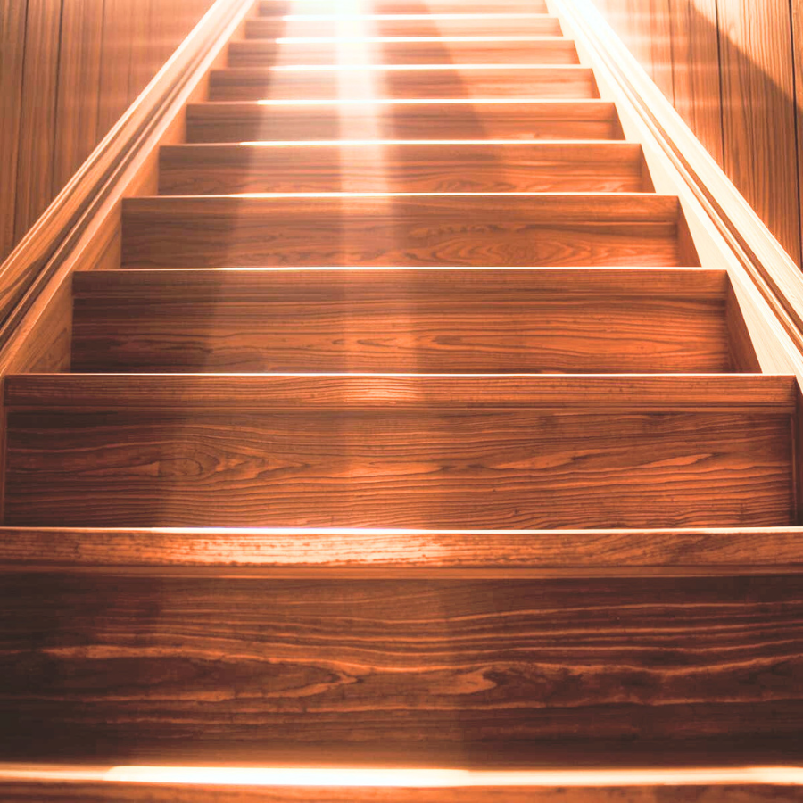 光の差す木の階段を下から見上げた構図