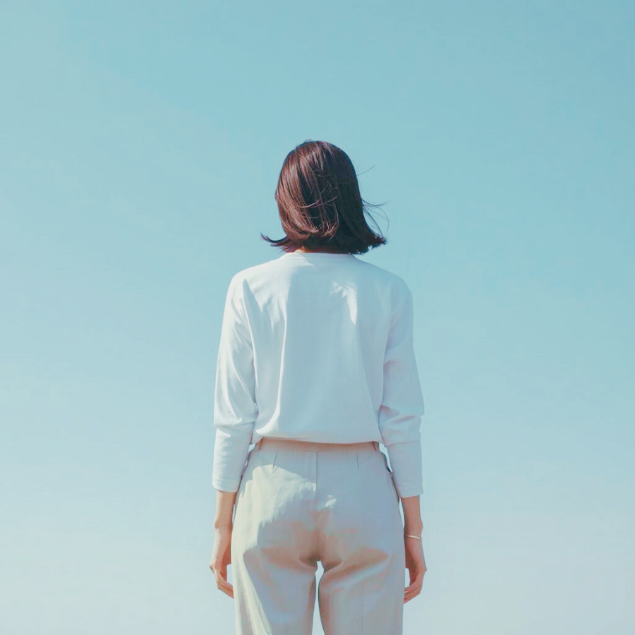 広い空の下で堂々と立つ女性の後ろ姿