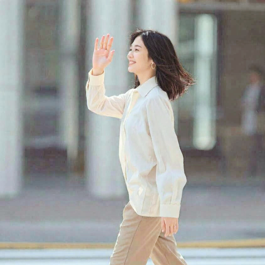 微笑みながら軽やかに歩き手を振る女性