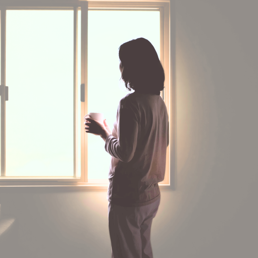 窓辺で立つ女性の後ろ姿。日常の立ち方に見られる体の偏り
