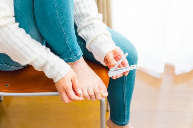 椅子に座り足の爪を切る女性